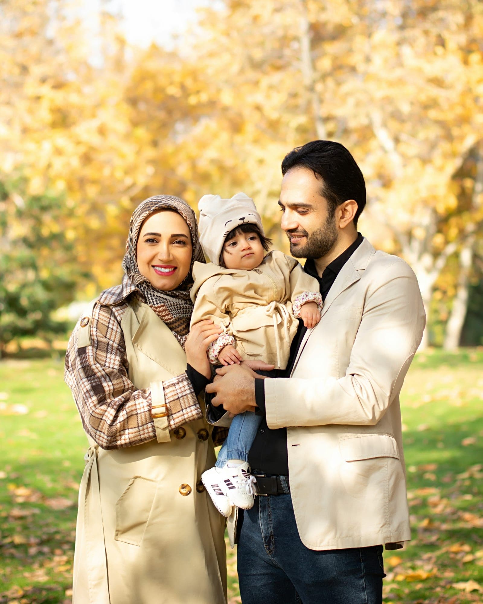 A smiling family with a toddler outdoors in autumn