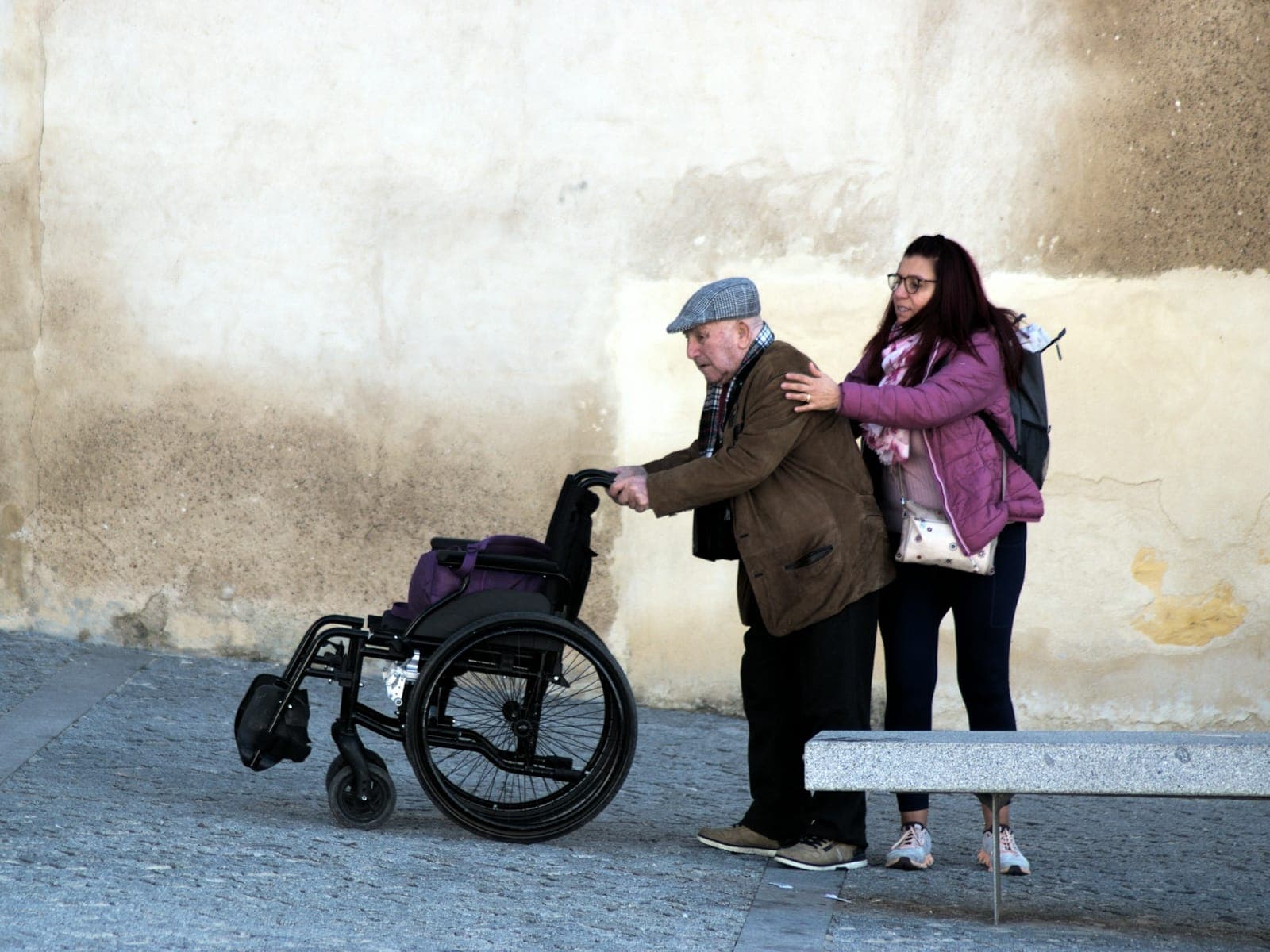 A young woman helps an older man using a wheelchair
