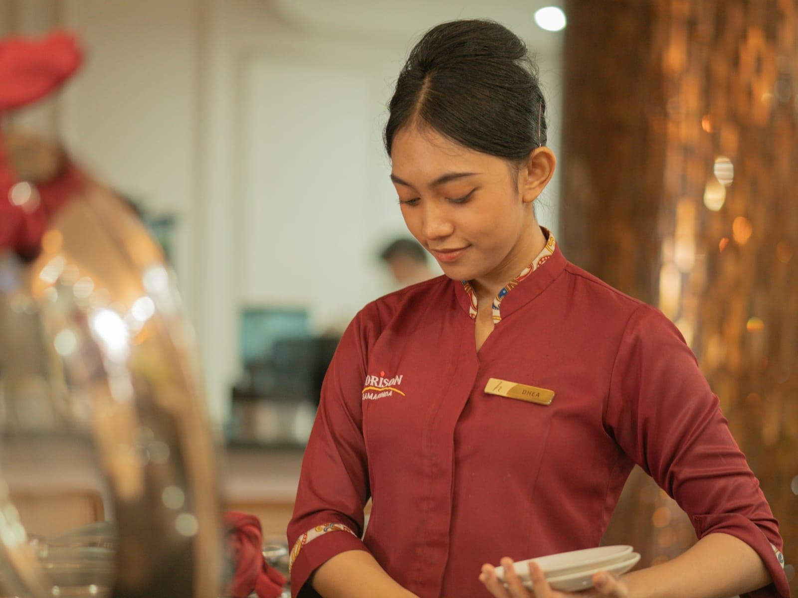 A hotel colleague in uniform prepares a restaurant table